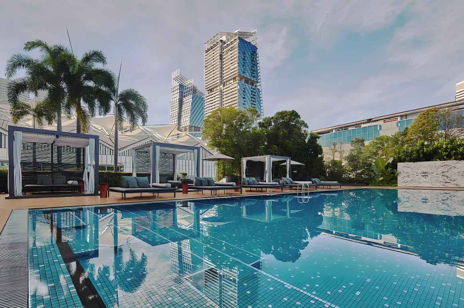 Luxury outdoor swimming pool with cabanas, palm trees, and modern skyscrapers in the background at a high‑end Singapore hotel.