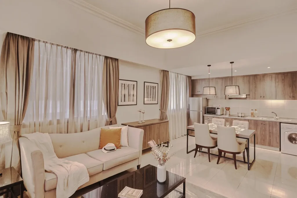 Spacious serviced apartment interior at Adina Singapore Orchard showcasing a cozy living area, dining space, and modern kitchen with wood finishes.