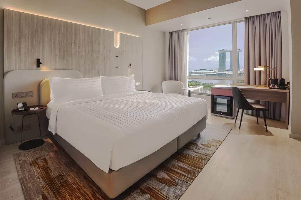 Modern hotel room with king bed and window view of Marina Bay Sands Singapore.