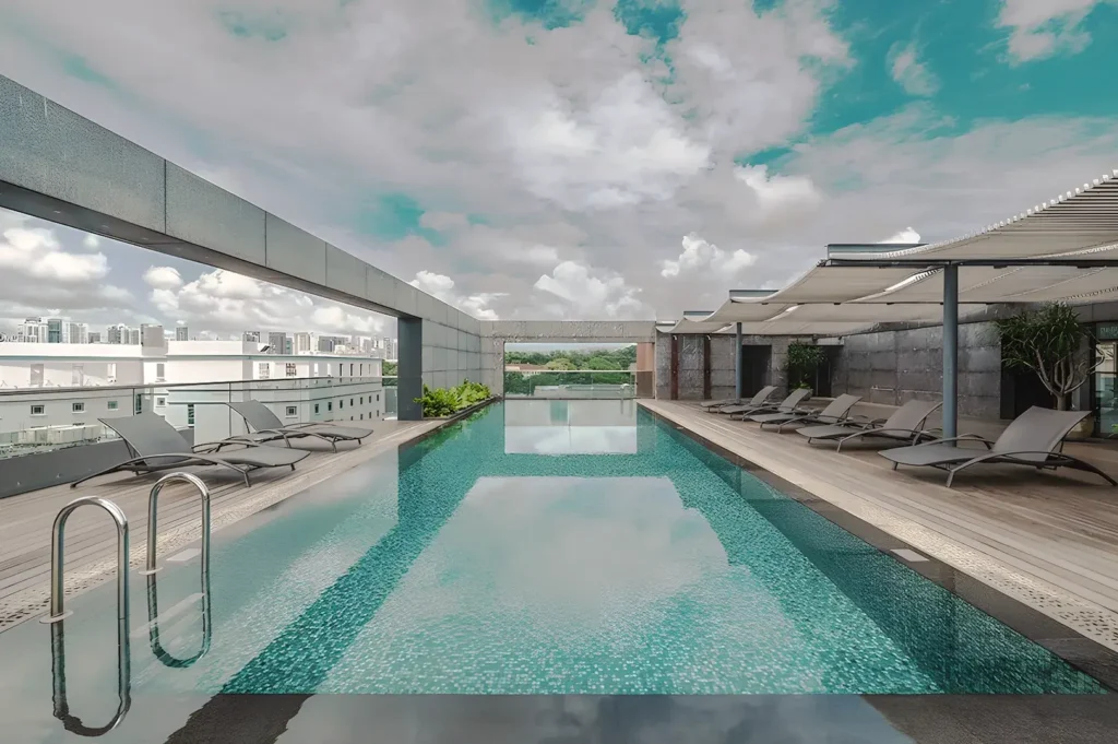 Rooftop infinity pool at 30 Bencoolen Hotel Singapore with lounge chairs, panoramic city views, and modern design under a bright tropical sky.