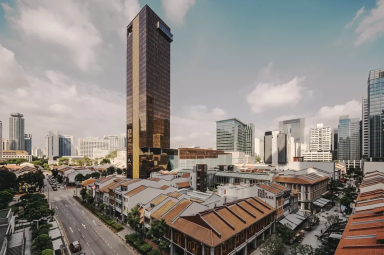 Aerial view of Far East Square in Singapore featuring a tall bronze skyscraper surrounded by heritage shophouses with red‑tiled roofs and modern city buildings — blending old‑world charm with urban sophistication.