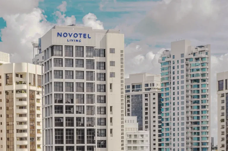 Novotel Living Singapore high‑rise building surrounded by modern apartments under a bright sky, showcasing contemporary urban architecture.