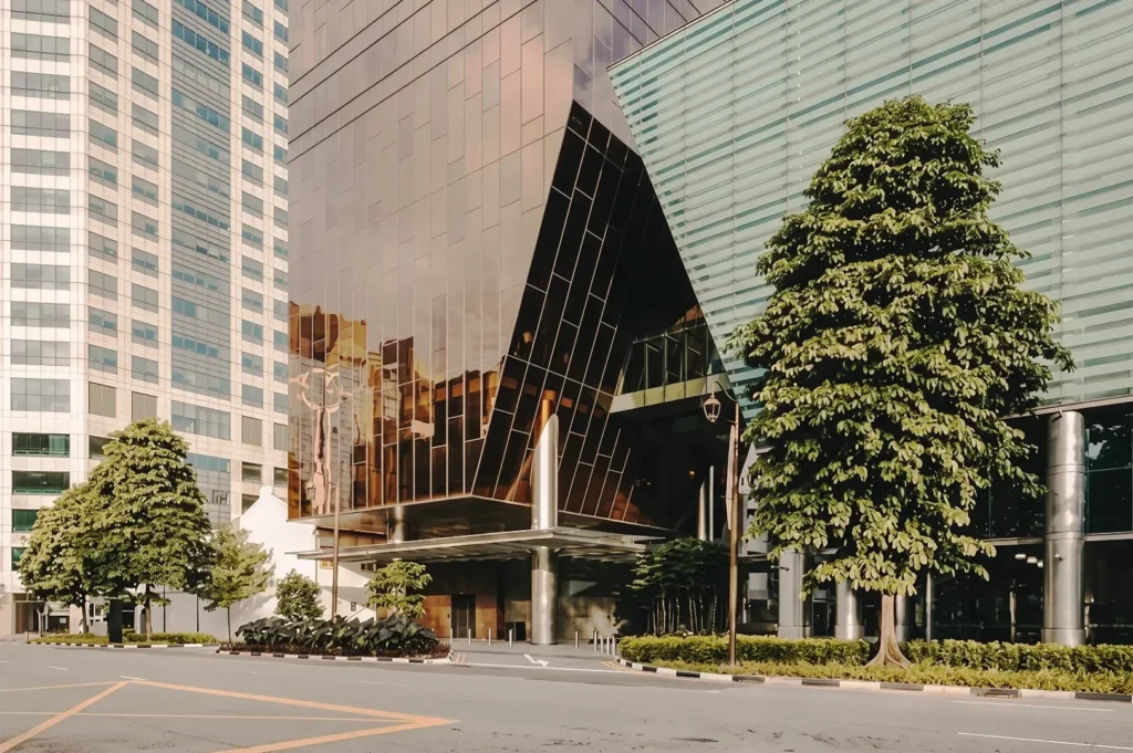 Modern building entrance in Singapore with reflective bronze glass architecture and lush greenery — highlighting contemporary design and urban sophistication.