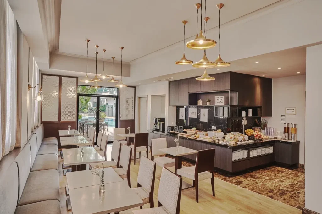Bright breakfast room at Adina Serviced Apartments Singapore Orchard featuring elegant pendant lighting, buffet counter, and poolside view.