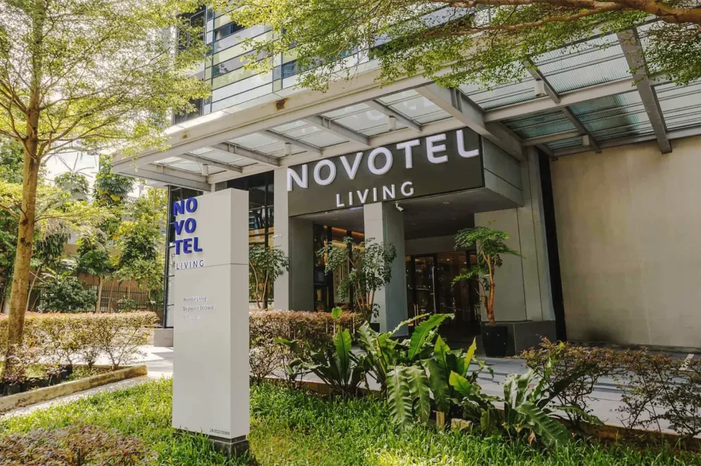 Exterior view of Novotel Living Singapore Orchard with branded signage, landscaped greenery, and sleek architectural design.