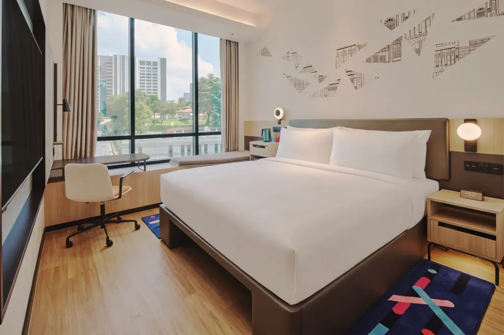 Contemporary Aloft hotel room in Singapore with king bed, large window view, minimalist furniture, and geometric wall art — stylish urban lodging.