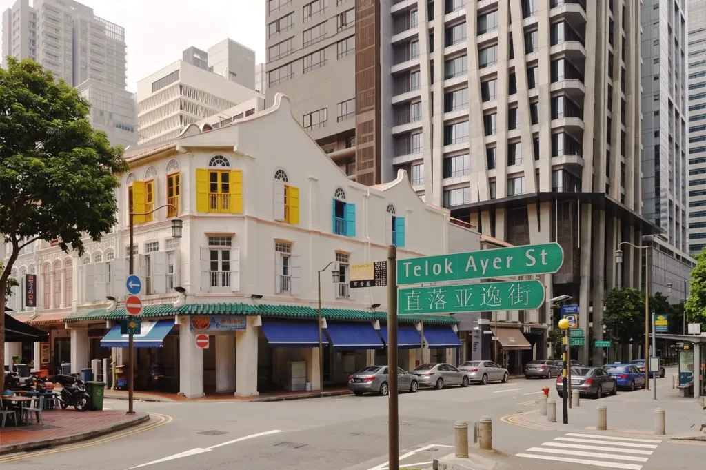 Colorful heritage shophouse at Telok Ayer Street, Singapore, with bright yellow and blue window shutters set against modern skyscrapers — showcasing the city’s architectural diversity and cultural vibrancy.