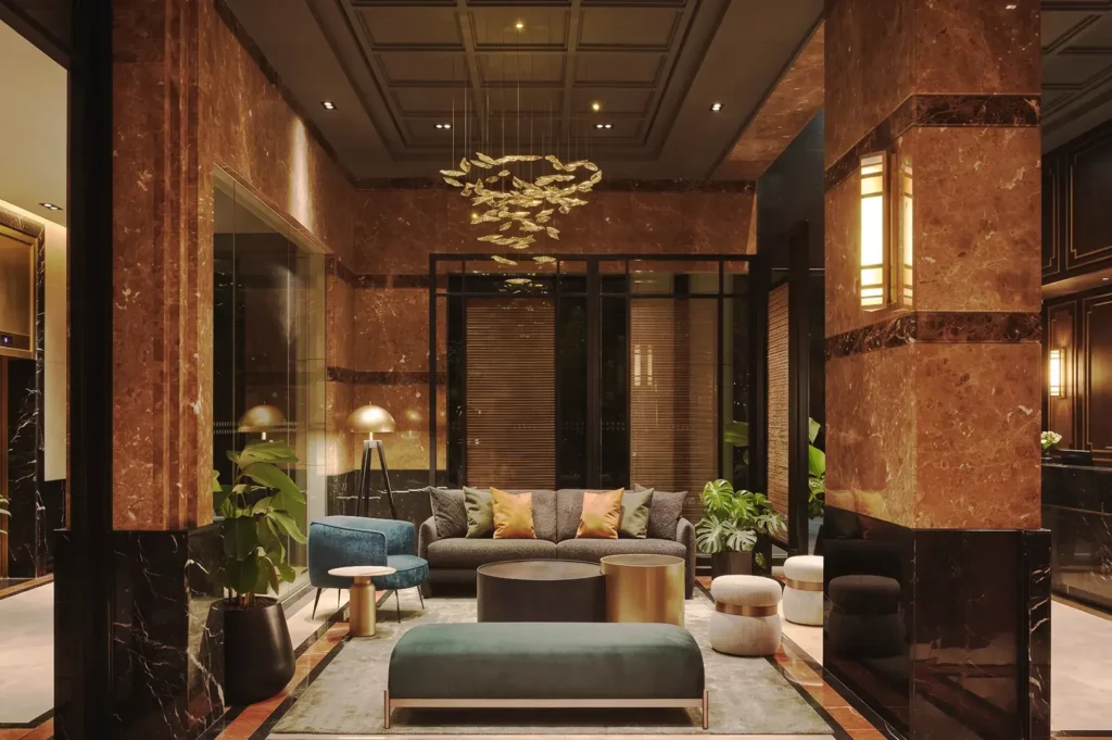 Chic lounge area at Adina Serviced Apartments Singapore Orchard with marble walls, designer furniture, and ambient golden lighting.
