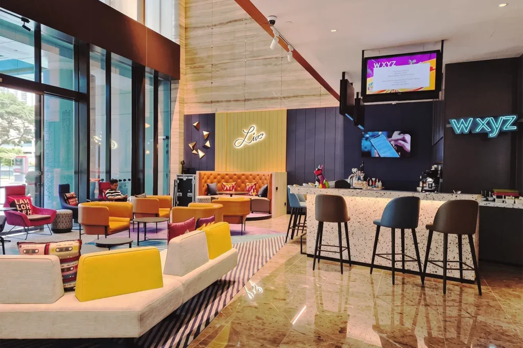 Colorful Aloft Singapore lobby with w xyz bar, neon signage, and vibrant seating — trendy social space for guests and travelers.