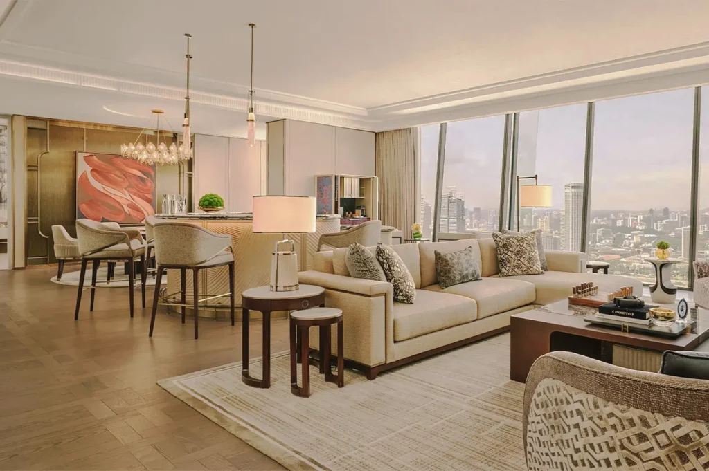 Elegant high-rise hotel suite in Singapore featuring beige modern furniture, panoramic city skyline views, and sophisticated interior design.