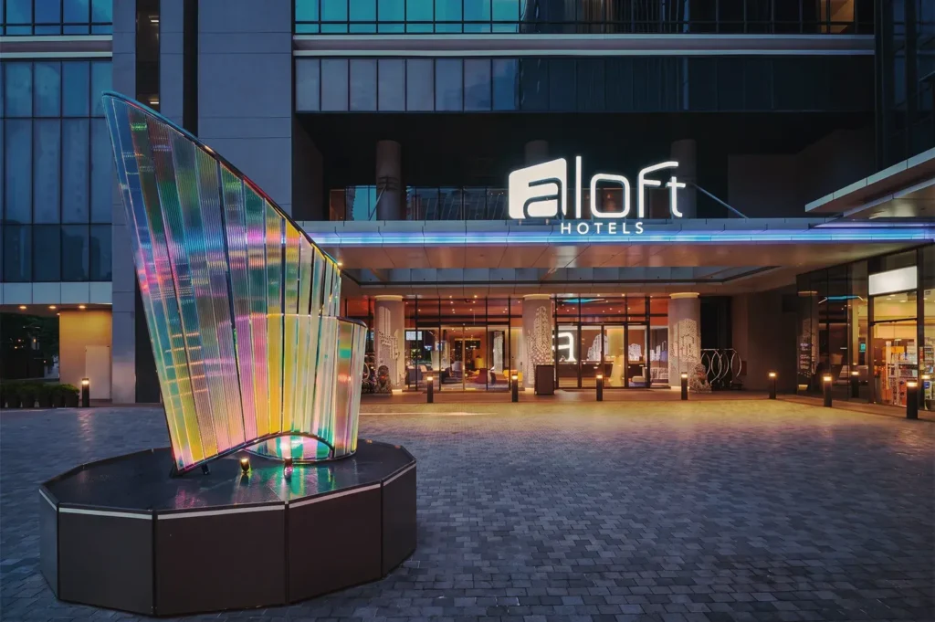 Front entrance of Aloft Hotels Singapore featuring illuminated signage and colorful glass sculpture — modern boutique hotel with vibrant design.