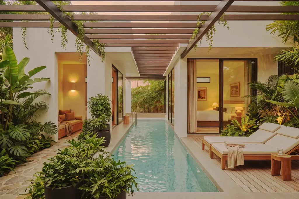 Private villa with narrow lap pool, tropical greenery, and modern architecture featuring glass doors and wooden pergola — serene luxury accommodation in Singapore.